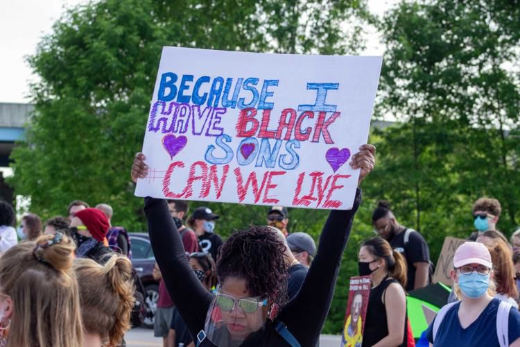 A protester raises a sign above her head during a demonstration outside of Indianapolis Metropolitan Police Department's Northwest District. (Photo/Tyler Fenwick)